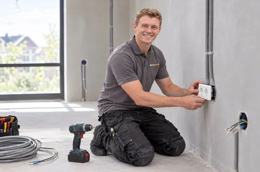 Monteur plaatst een dubbel stopcontact in een gestucte wand in een nieuwbouwwoning