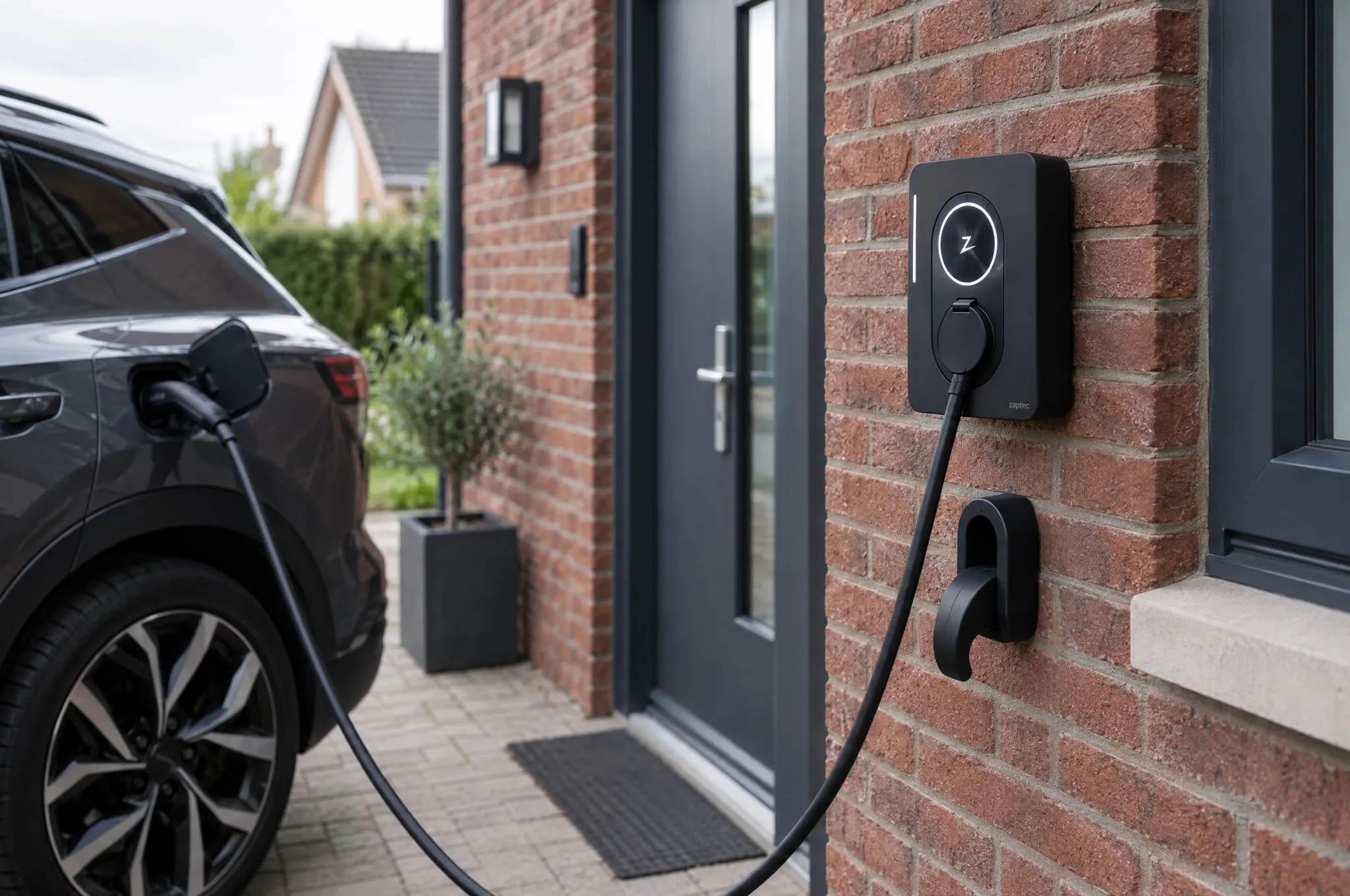 Zaptec Go 2-laadpaal aan de bakstenen gevel van een woning, met een elektrische auto aan de laadkabel